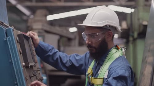 Man Operates Machinery in an Industrial Factory