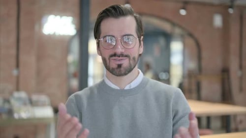 Smiling Man Talking Indoors In Gray Sweater and Glasses