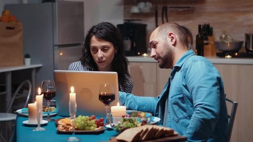 Couple Using Laptop at Dinner Table with Candles