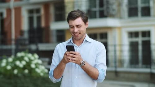 Smiling Man Using Phone on City Street