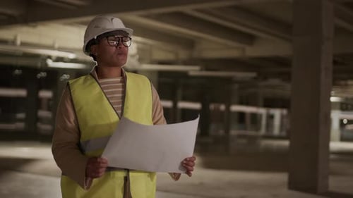 Focused Woman Reviews Construction Plans Indoors
