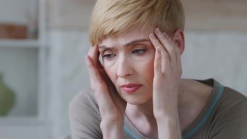 Le visage d'une femme bouleversée, malheureuse, déprimée et misérable se frotte au temple et souffre de tensions