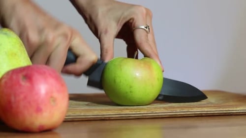 Woman Cuts Green Apple on Cutting Board