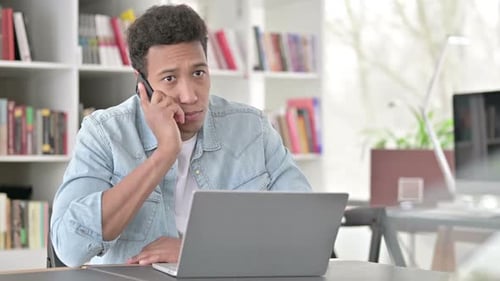 Young Adult Talking on Phone at Desk
