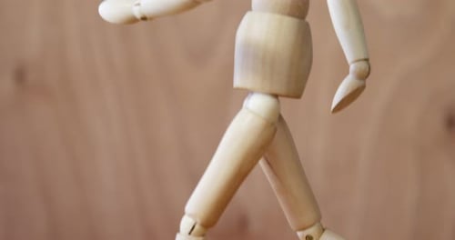 Wooden Mannequin Walking in Place on Wood Surface
