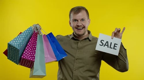 Man Cheerful with Sale Sign and Shopping Bags