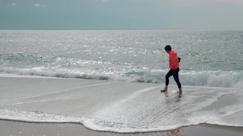 Female is walking on empty sandy beach