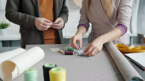 Nahaufnahme von Schneidern von Mädchen und Männern, die Stoffe und Fäden für neue Kleidungsstücke auswählen