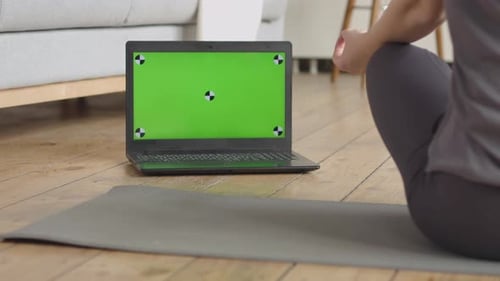 Woman Meditating with Laptop Green Screen at Home