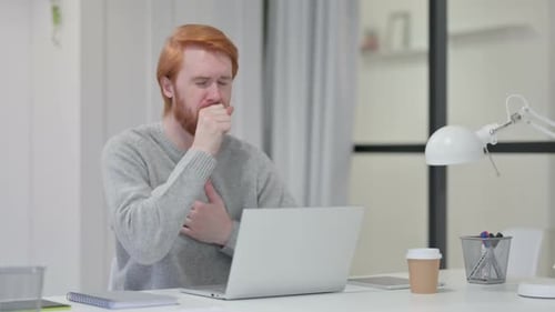 Man Coughing While Using Laptop at Desk