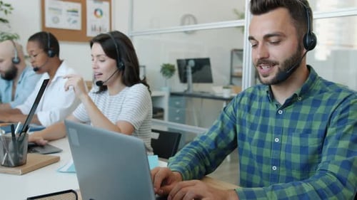 Handsome Man Call Center Agent Talking to Client Using Laptop Then Taking Notes