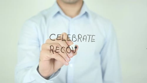 Man Writes Celebrate Recovery On Clear Surface