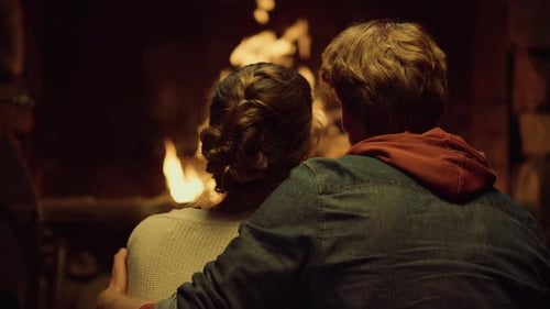 Romantic Couple Sitting near a Warm Fireplace Indoors