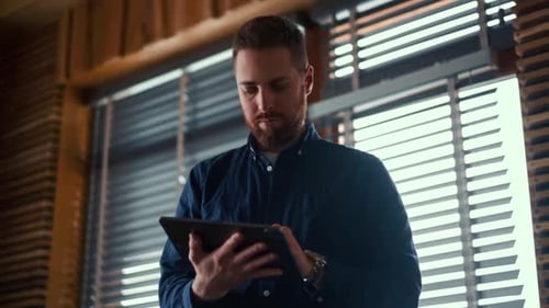 Man Using Tablet Device Indoors by Window