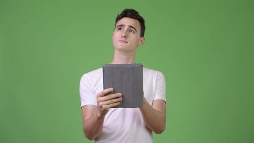 Man Holding Tablet Thinking in Front of Greenscreen