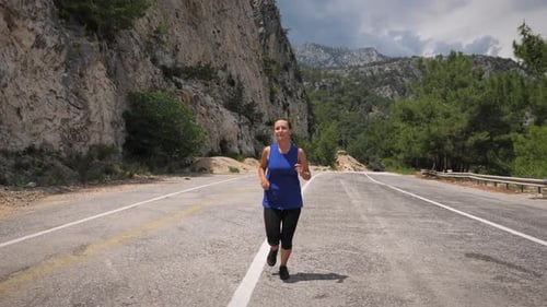 Woman Running on Road in Mountainous Landscape