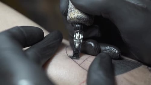 Erfahrener Tattoo-Salon-Arbeiter in Handschuhen trägt schwarze