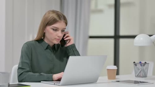 Woman Works on Laptop and Talks on Phone