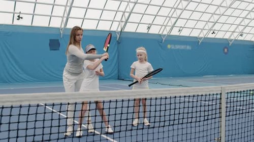 Tennis Coach Trains Young Girls on Indoor Court