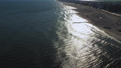 aerial drone shot tilting up with a crane rise up over glistening sunset over ocean