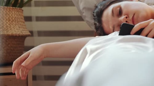 Woman Rests in Bed Using Cellphone