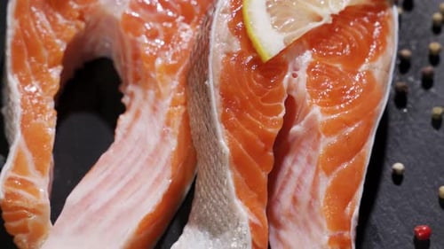 Frisches Stück Lachs auf Schneidebrett auf Küchentisch mit Gewürzen Zitrone