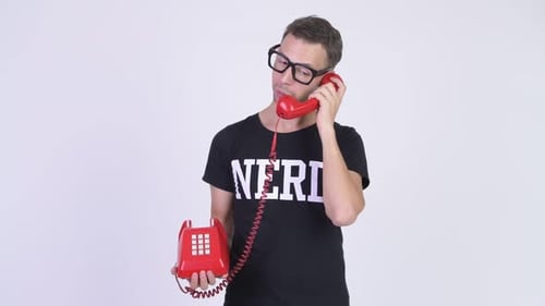 Studio Shot of Happy Nerd Man Thinking While Talking on Telephone