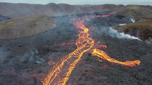 Islândia. Erupção do vulcão. Lava quente derretida fluindo da cratera através de fluxos de lava na encosta.