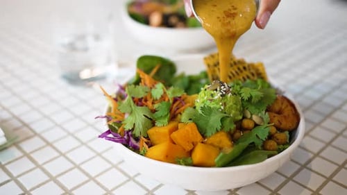 Pouring Sauce onto a Colorful Vegan Salad