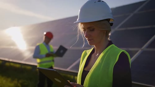 Portrait d'une ingénieure solaire debout utilisant une tablette et regardant la caméra d'un autre homme