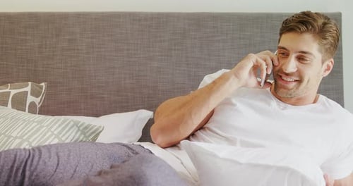 Young Man Chatting on Phone Lying on Bed