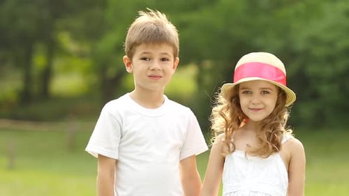 Children Walking in the Park Are Holding Hands and Looking Into the Distance. Slow Motion