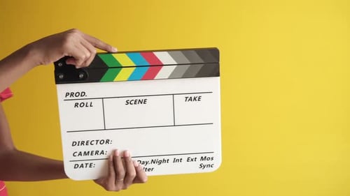Sosteniendo la placa de clapper de película contra la pared blanca