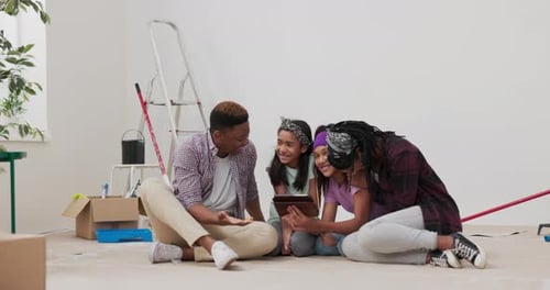 Family Smiles and Looks at Tablet Indoors