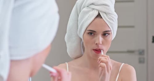 Woman Brushing Teeth in Bathroom Mirror