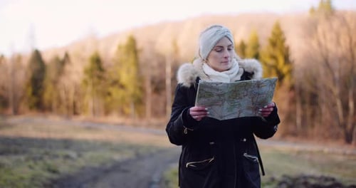 Woman Using Map in Sunny Woodland Area