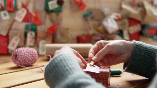 Person Prepares Christmas Gift with Tag and String