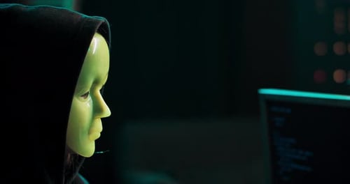 Masked Person Coding at Computer at Night