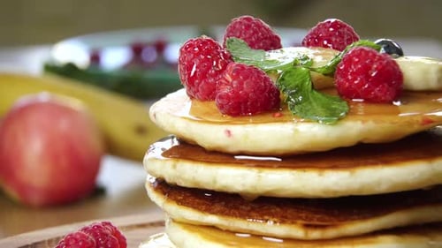 Delicious Pancakes with Raspberries and Syrup Close Up