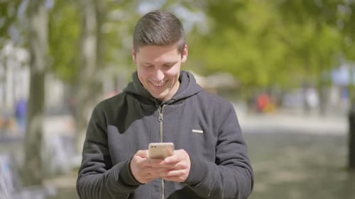 Smiling Man Using Smartphone in Urban Park