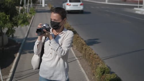 Woman Wearing Mask Taking Pictures on City Street
