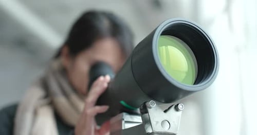 Mujer joven observa a través del telescopio