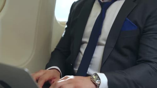 Man Typing on Laptop in Airplane Cabin