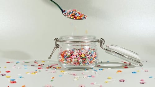Colorful Candy Confectionery Run Poured Into a Jar Glass on Green Background