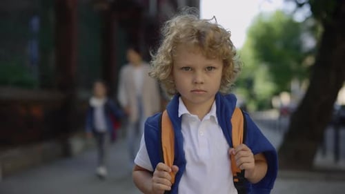Portrait of a Little Schoolboy with a Backpack Standing on School Yard Holding Bag Turn Around and