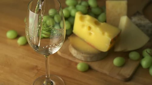 Pouring White Wine with Cheese and Green Grapes