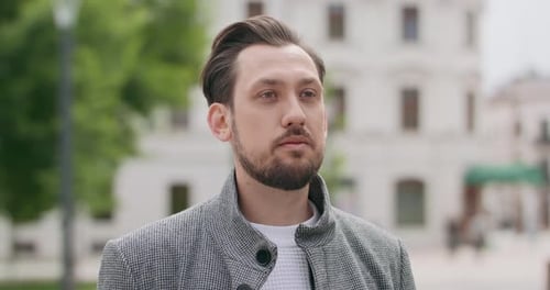 Junger Mann mit Schnurrbärten und Bart hält ernstes Gesicht und dreht dann das Gesicht zur Kamera und