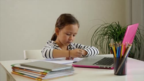 Child Doing Schoolwork with Laptop and Notebook