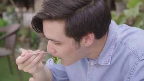 Young Man Eating a Fresh Salad Outdoors