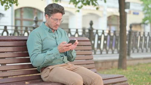 Man Using Mobile Phone on a Park Bench